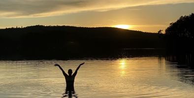 Person standing in Togue Pond at sunset
