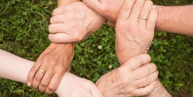 Six hands holding onto each other's wrists.