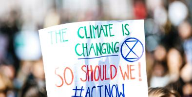 Person holding sign "The Climate is changing so should we # Actnow"