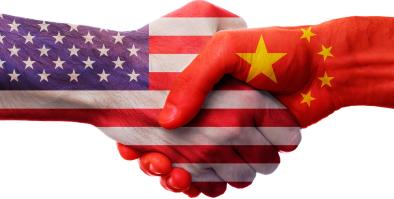 two hands, each painted like the flag of the USA and China, shaking in greeting.