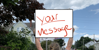 Person holding sign with the words - your message - above their head.  Blue sky - quiet street.
