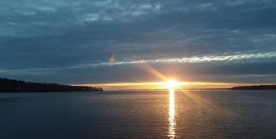 sunset over the ocean with land on either side.